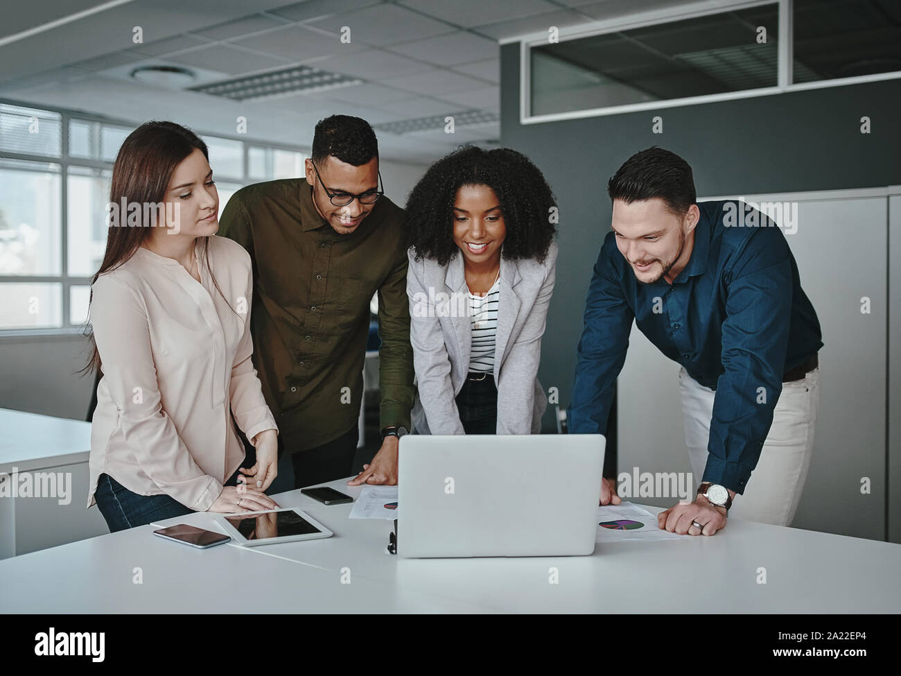 Lächelnd multiethnischen Kollegen zusammen arbeiten im Büro gerade online Projekt Anwendung auf Laptop über das Büro Schreibtisch Stockfoto