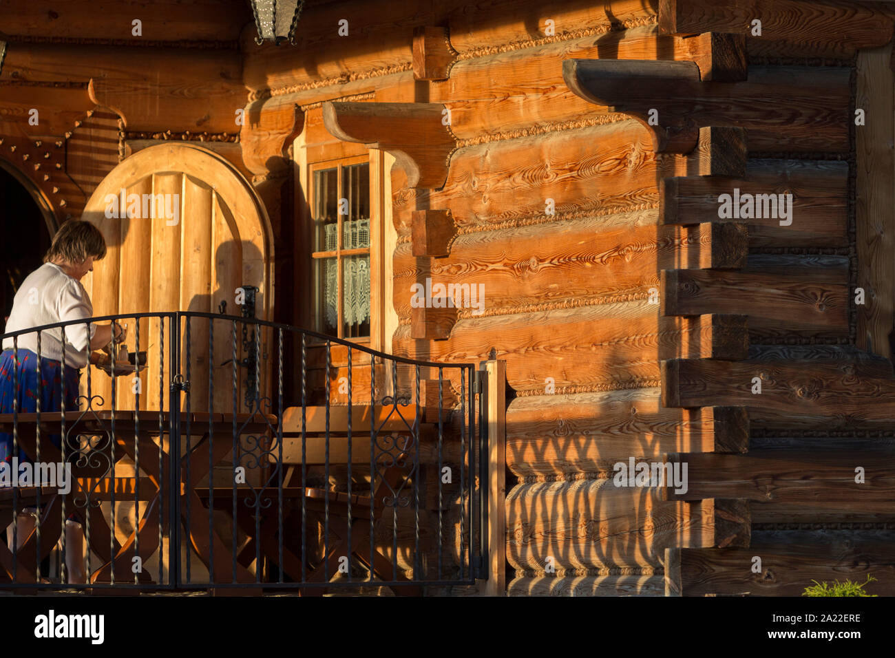 Eine Kellnerin Löscht eine Tabelle im späten Nachmittag Sonne außerhalb der Bocowka Restaurant, einem traditionellen mountain Log Cabin im südlichen Polen, am 21. September 2019, in Jaworki, in der Nähe von Szczawnica, Malopolska, Polen. Stockfoto