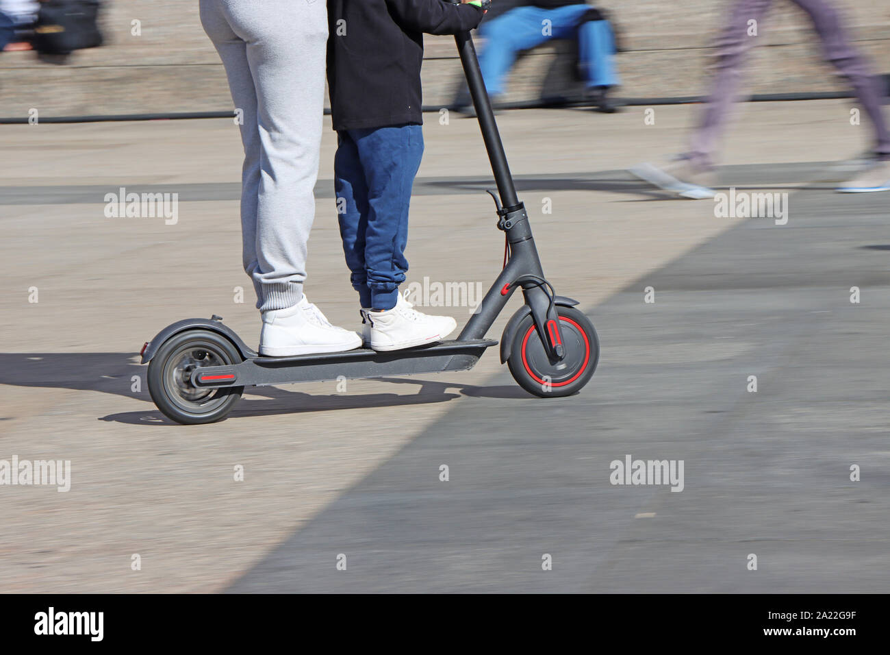 Mutter und Sohn, elektrische Kick scooter am City Square, verschwommene Bewegung Stockfoto