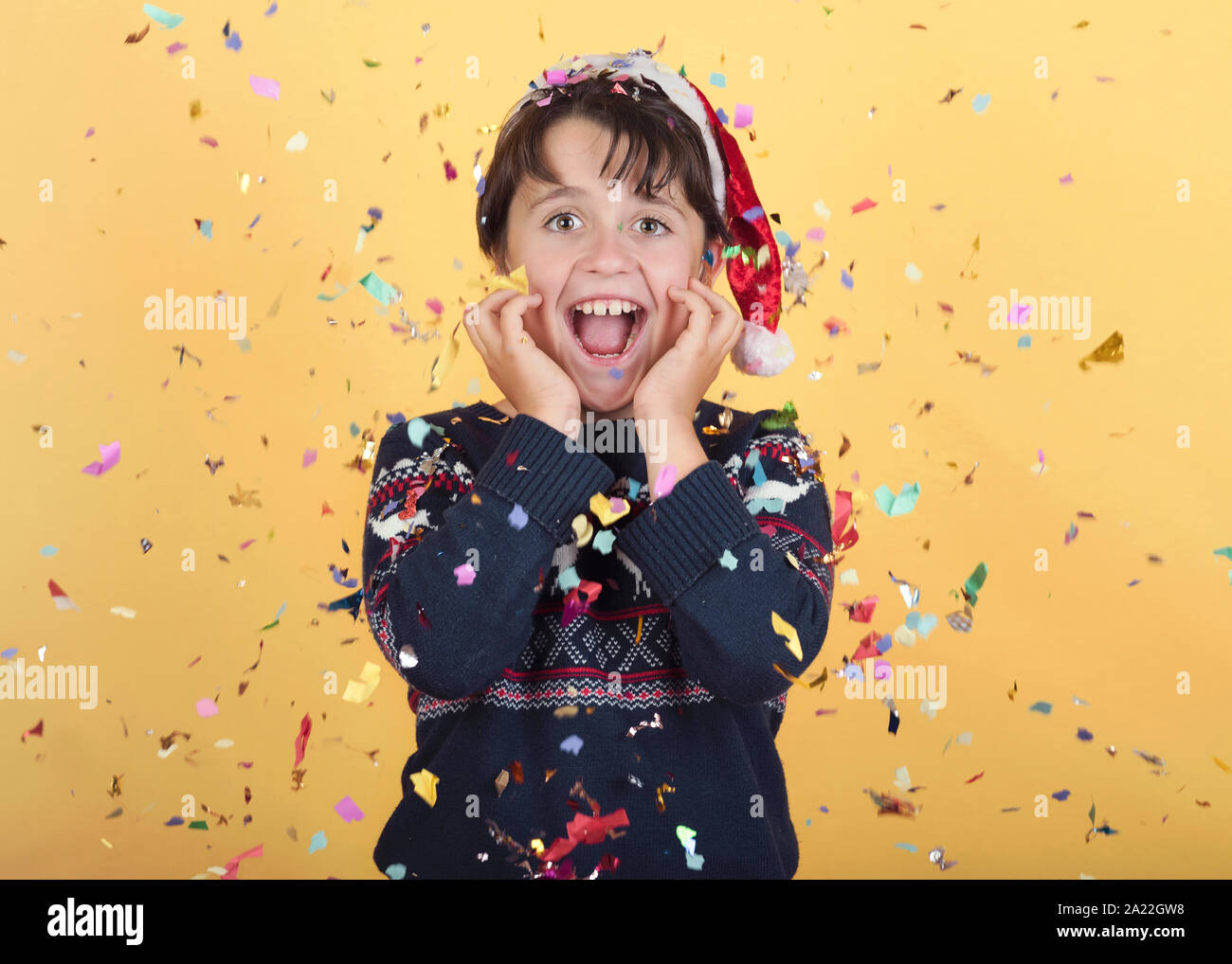Lächelnd Kind mit Konfetti tragen Weihnachten Santa Claus hat auf gelbem Hintergrund Stockfoto