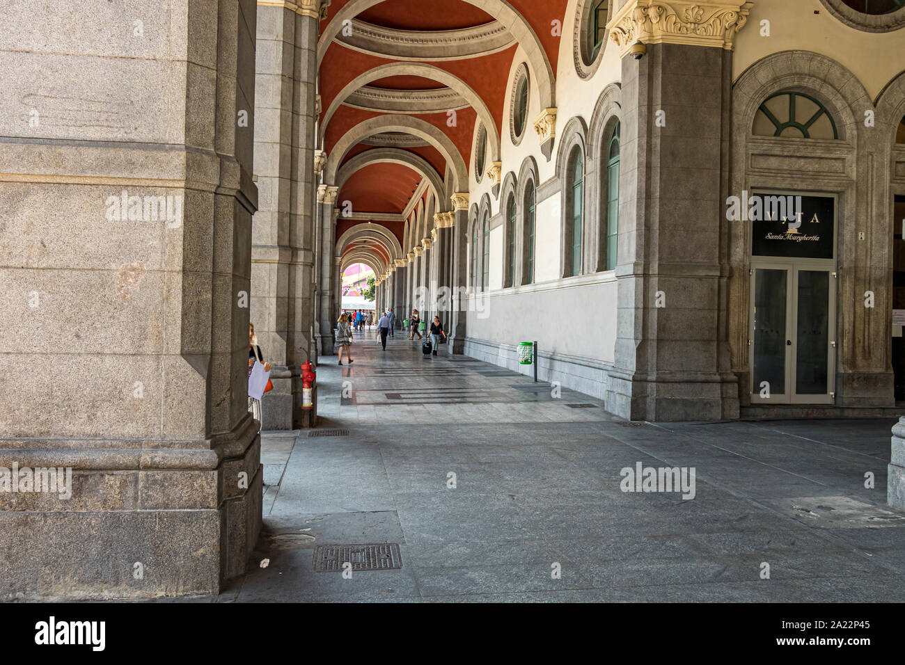 Die Leute laufen durch den eleganten, gewölbten Säulengang in der Nähe des Haupteingangs zu Porta Nuova, einem großen Bahnhof in Turin, Italien Stockfoto