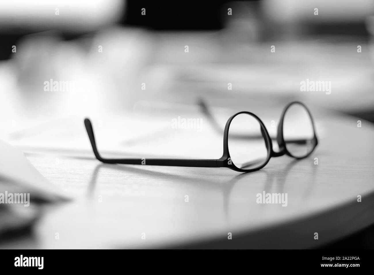 Gläser mit einem schwarzen Rahmen liegen auf dem Schreibtisch im Büro Stockfoto