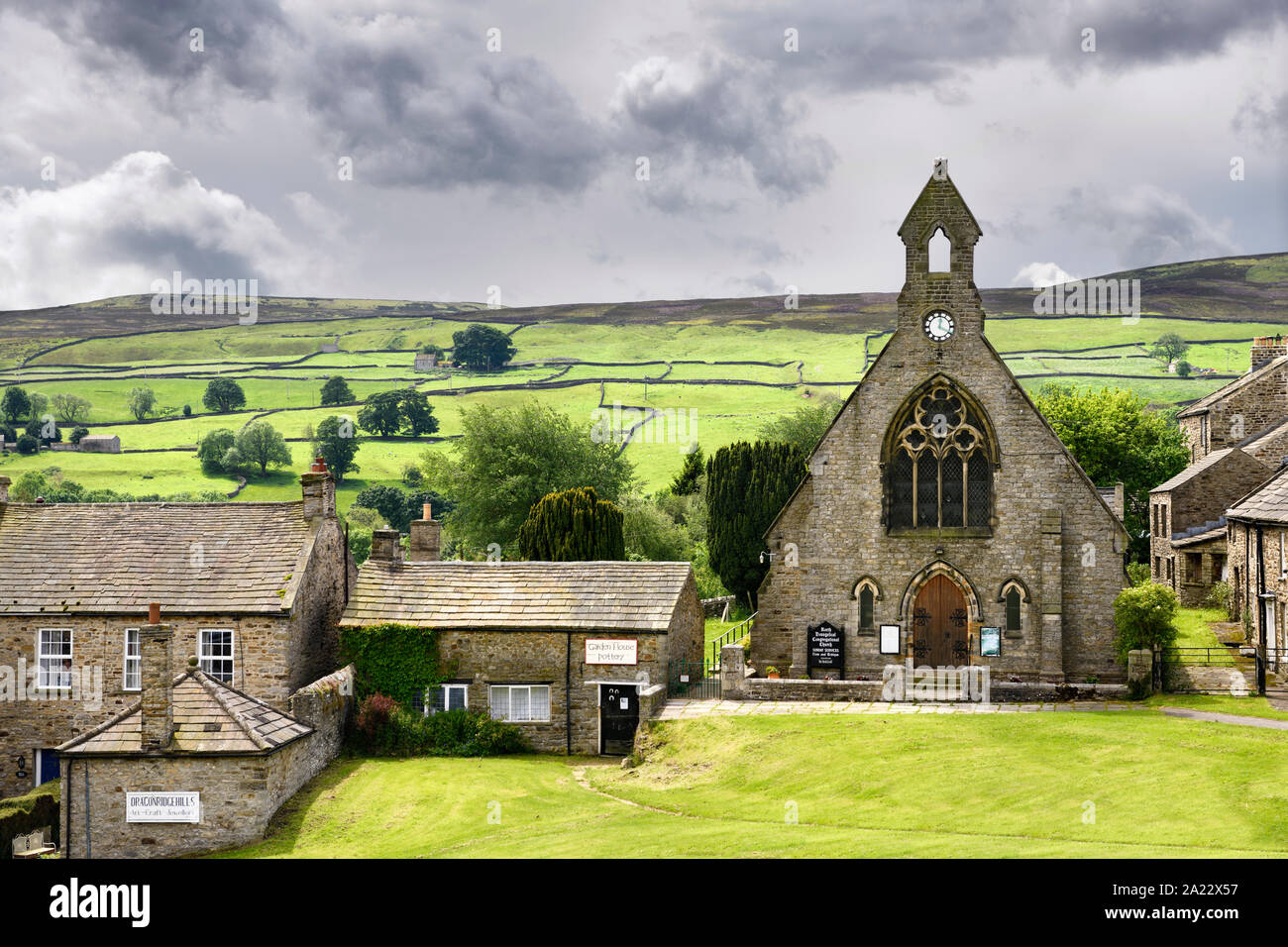 Grüne Weideflächen für Schafe mit Trockenmauern hinter Gemeindekirche in Reeth North Yorkshire England Stockfoto