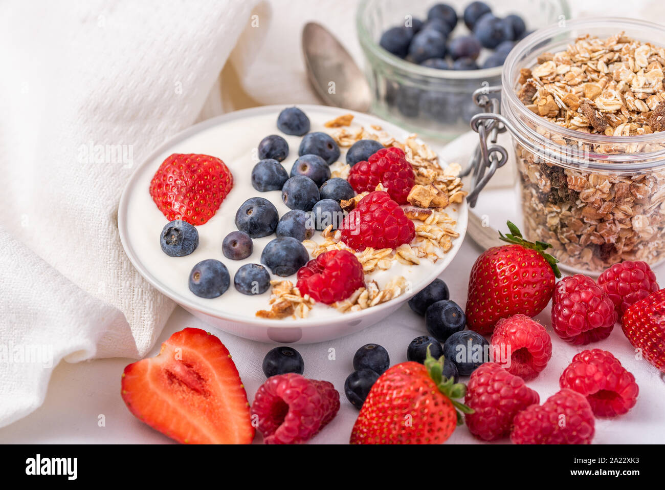 Weißer Joghurt in der Schüssel mit Haferflocken und Erdbeeren, Heidelbeeren und Himbeeren auf der Oberseite. Stockfoto