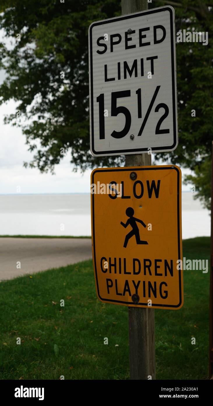 Höchstgeschwindigkeit 15 1/2 und langsam Spielende Kinder Schilder mit See land Hintergrund, Hochformat Stockfoto