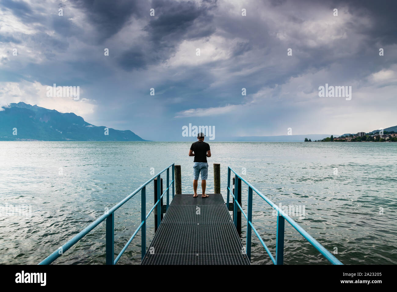 Mann steht auf einer Plattform am Genfer See in der Ferne dunkle Wolken und Regen, Montreux, Schweiz. Stockfoto