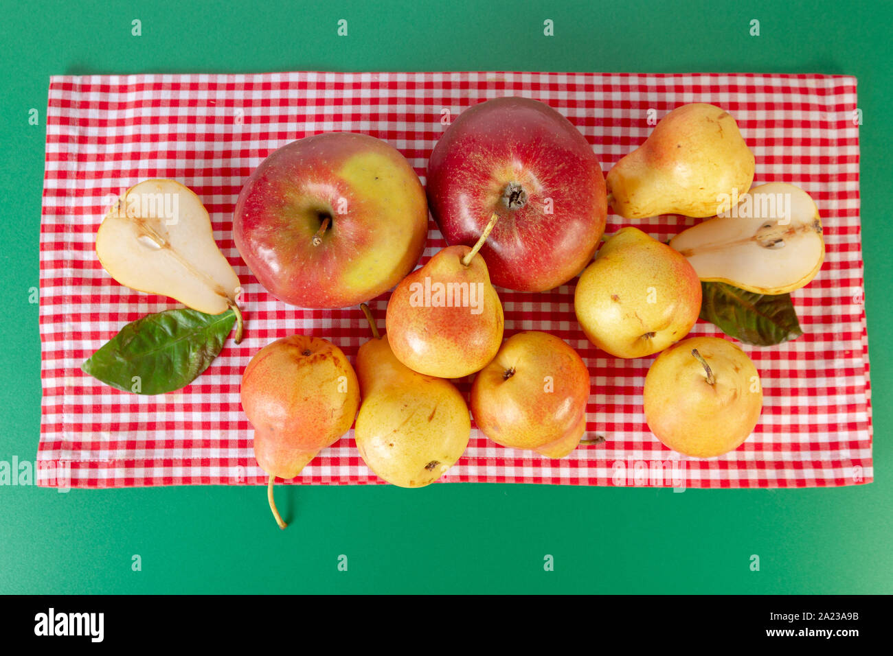 Birnen und Äpfel flach auf grünen Tisch legen mit Rot karierte Tischdecke. Herbst noch leben. Rustikales Design. Stockfoto