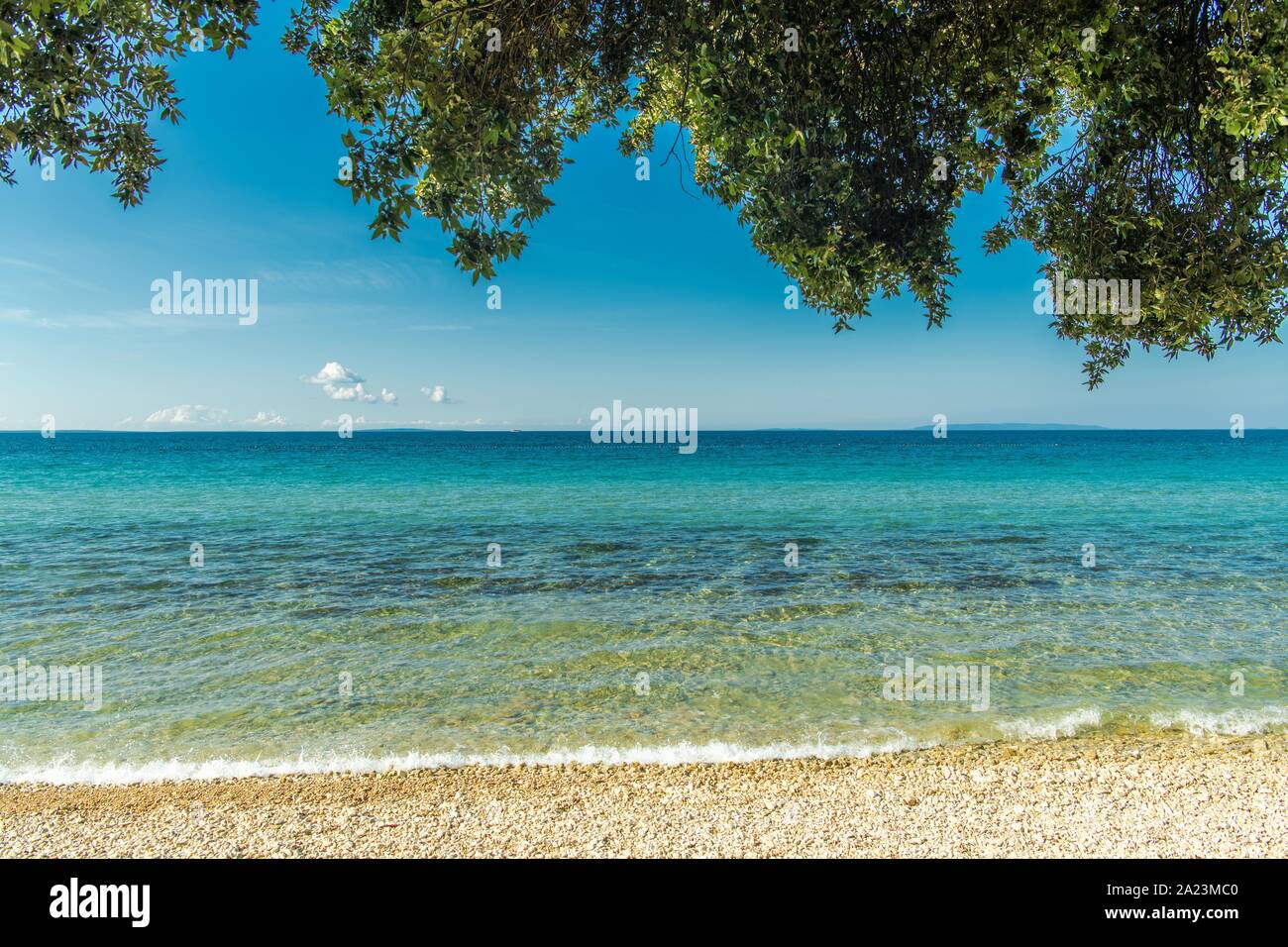 Sonnige malerische Strand an der Adria. Das kristallklare türkisfarbene Wasser, felsige Küste und Äste auf der Oberseite. Ferienhäuser Reise Hintergrund. Novalja, Croa Stockfoto