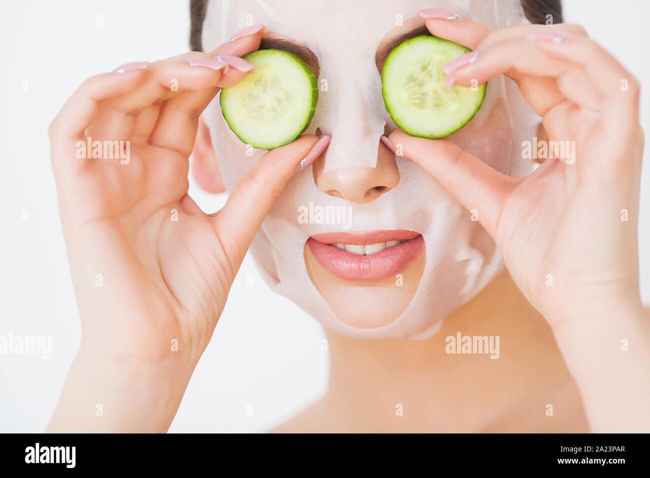 Schöne junge Frau in Ton Schlamm Maske auf das Gesicht, die Augen mit Scheiben Gurke. Stockfoto
