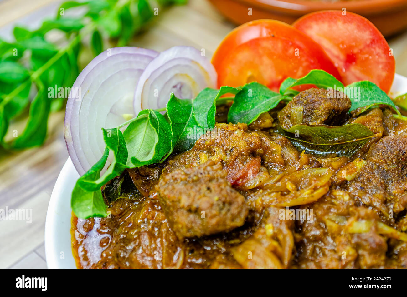 Nahaufnahme von Spicy Beef curry mit Zwiebeln garniert, Curry Blätter & Tomate. Traditionelle South Indian (Kerala) Küche. Stockfoto