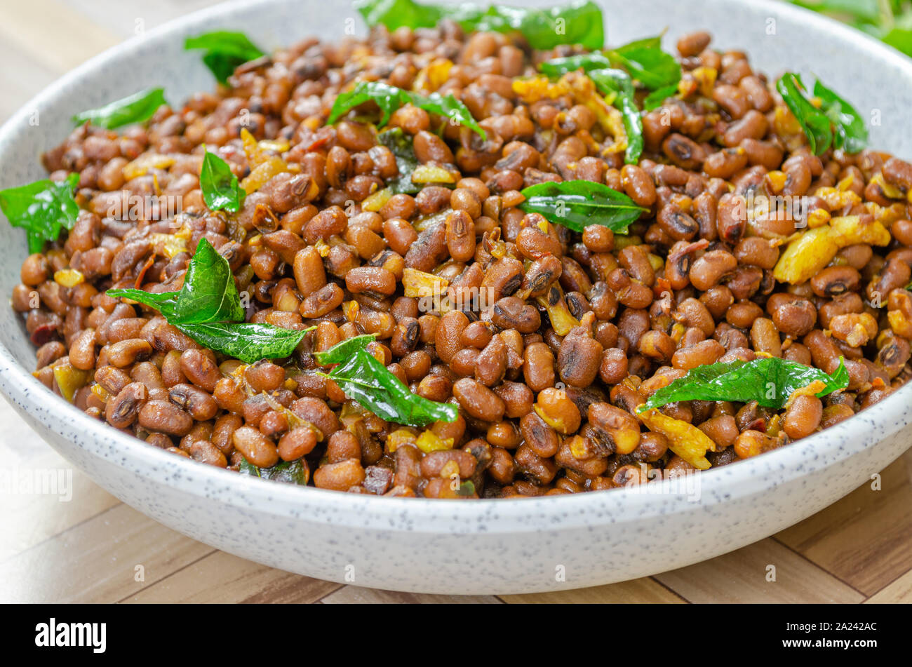 Red Cow Erbsen curry mit sautierten curry Blätter in eine Schüssel geben. Makroaufnahme. Stockfoto