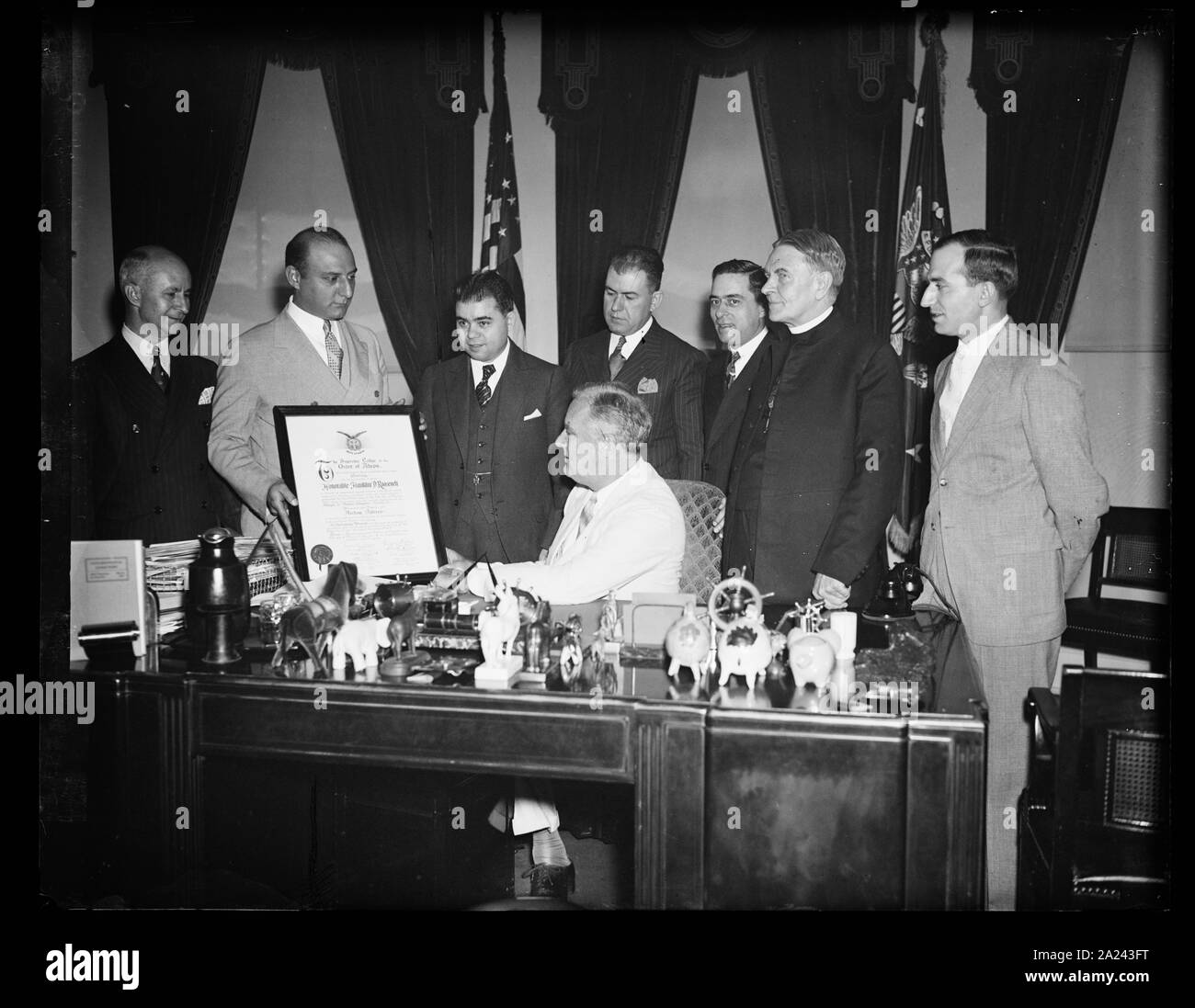 Präsident empfängt Brüderlichkeit Mitgliedschaft blättern. WASHINGTON, D.C., am 24. Juni. Präsident Roosevelt erhielt heute eine Schriftrolle in VERTRETUNG SEINER MITGLIEDSCHAFT IN DER GRIECHISCHEN REIHENFOLGE DER AHEPA. Er wurde initiiert, IN DER REIHENFOLGE, März 11, 1931, ALS GOUVERNEUR VON NEW YORK. Die griechischen PÄDAGOGISCHE VERBINDUNG BILDETE DIE DARSTELLUNG DURCH ARTHUR G. SYRAN, NEW YORK, Präsident. IN DER FOTOGRAFIE, L bis R: Johannes DOUNOUCOS, ARTHUR G. VOUCHELAS SYRAN, Peter, Präsident Roosevelt, CONSTANTINE G. ECONOMON, EL POLITES, REV. THOMAS J. LACEY, UND THOMAS PALEDES Stockfoto