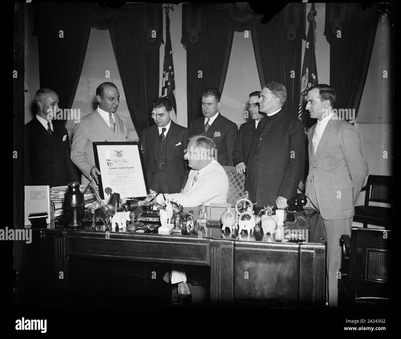 Präsident empfängt Brüderlichkeit Mitgliedschaft blättern. WASHINGTON, D.C., am 24. Juni. Präsident Roosevelt erhielt heute eine Schriftrolle in VERTRETUNG SEINER MITGLIEDSCHAFT IN DER GRIECHISCHEN REIHENFOLGE DER AHEPA. Er wurde initiiert, IN DER REIHENFOLGE, März 11, 1931, ALS GOUVERNEUR VON NEW YORK. Die griechischen PÄDAGOGISCHE VERBINDUNG BILDETE DIE DARSTELLUNG DURCH ARTHUR G. SYRAN, NEW YORK, Präsident. IN DER FOTOGRAFIE, L bis R: Johannes DOUNOUCOS, ARTHUR G. VOUCHELAS SYRAN, Peter, Präsident Roosevelt, CONSTANTINE G. ECONOMON, EL POLITES, REV. THOMAS J. LACEY, UND THOMAS PALEDES Stockfoto
