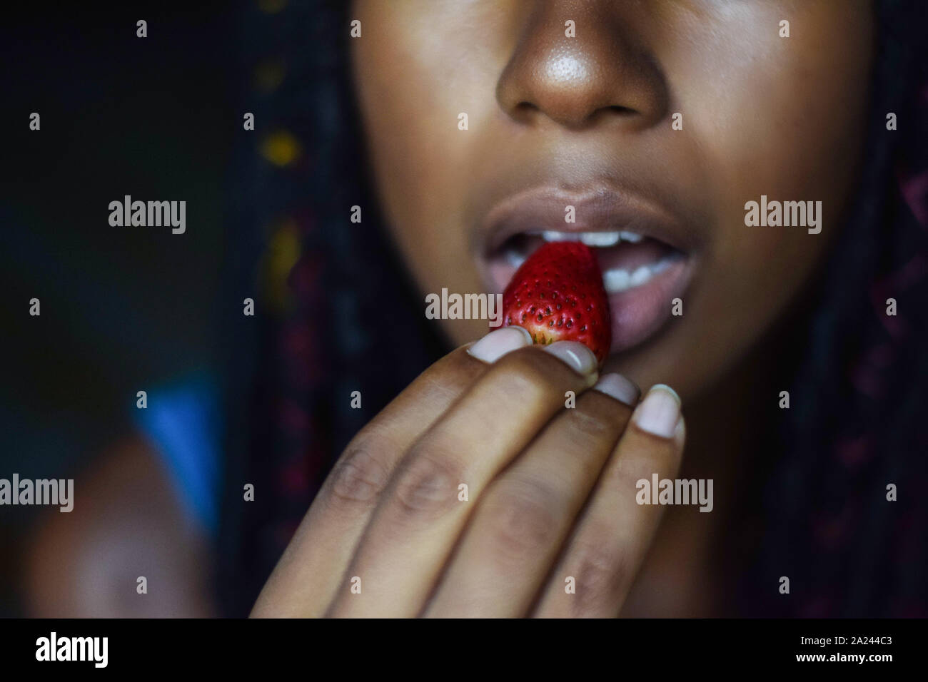 Junge schwarze Frau essen eine Erdbeere, Cali, Kolumbien Stockfoto