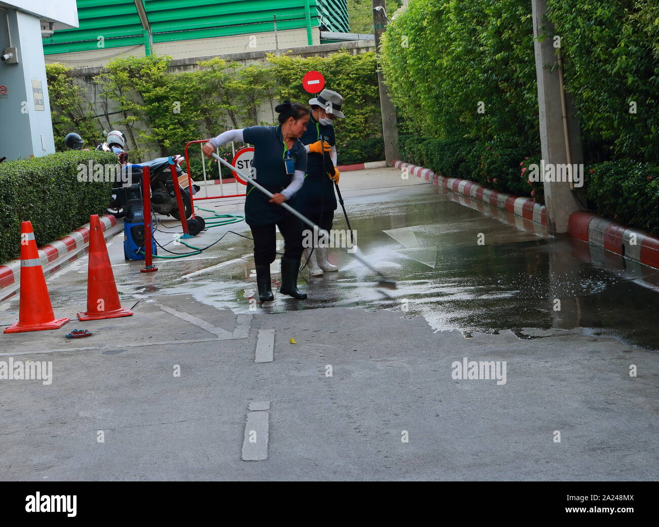 Bangkok, Thailand - 28. September 2019: verschwommene Bewegung einer Arbeitnehmerin Reinigung Den Boden mit Mop, während das andere verwendet Hochdruckreiniger Spra Stockfoto