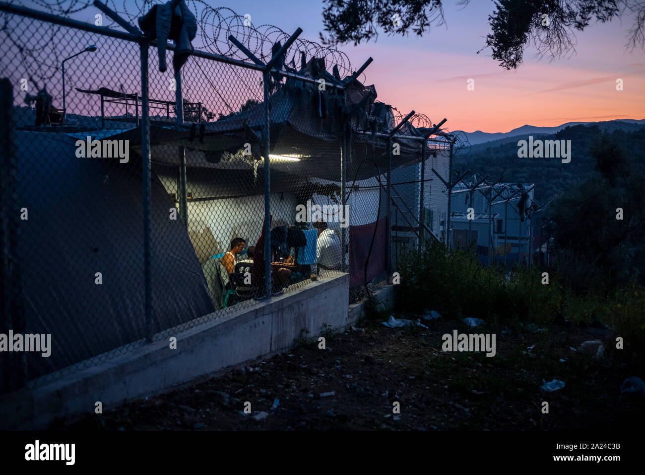 Athen, Griechenland. 26 Sep, 2019. Migranten sitzen in den Moria Camp auf der Insel Lesbos neben einem Stacheldrahtzaun. Credit: Angelos Tzortzinis/dpa/Alamy leben Nachrichten Stockfoto