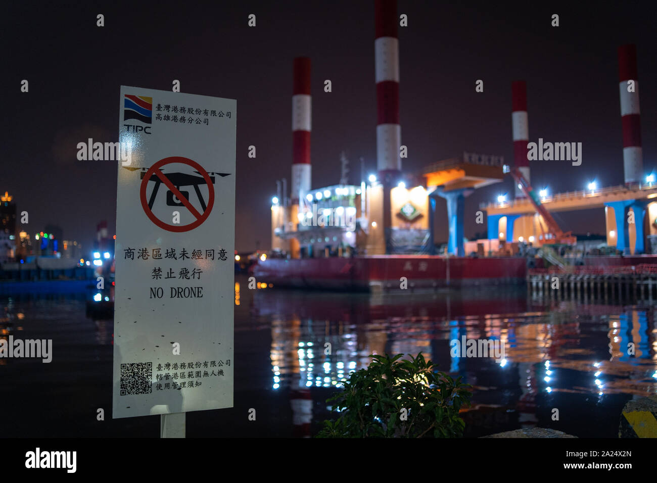 Eine "Kein Drone"-Zeichen in der chinesischen verbietet, Drohnen mit einem Industriehafen Bereich im Hintergrund in der Nacht zu fliegen. Fly Stockfoto