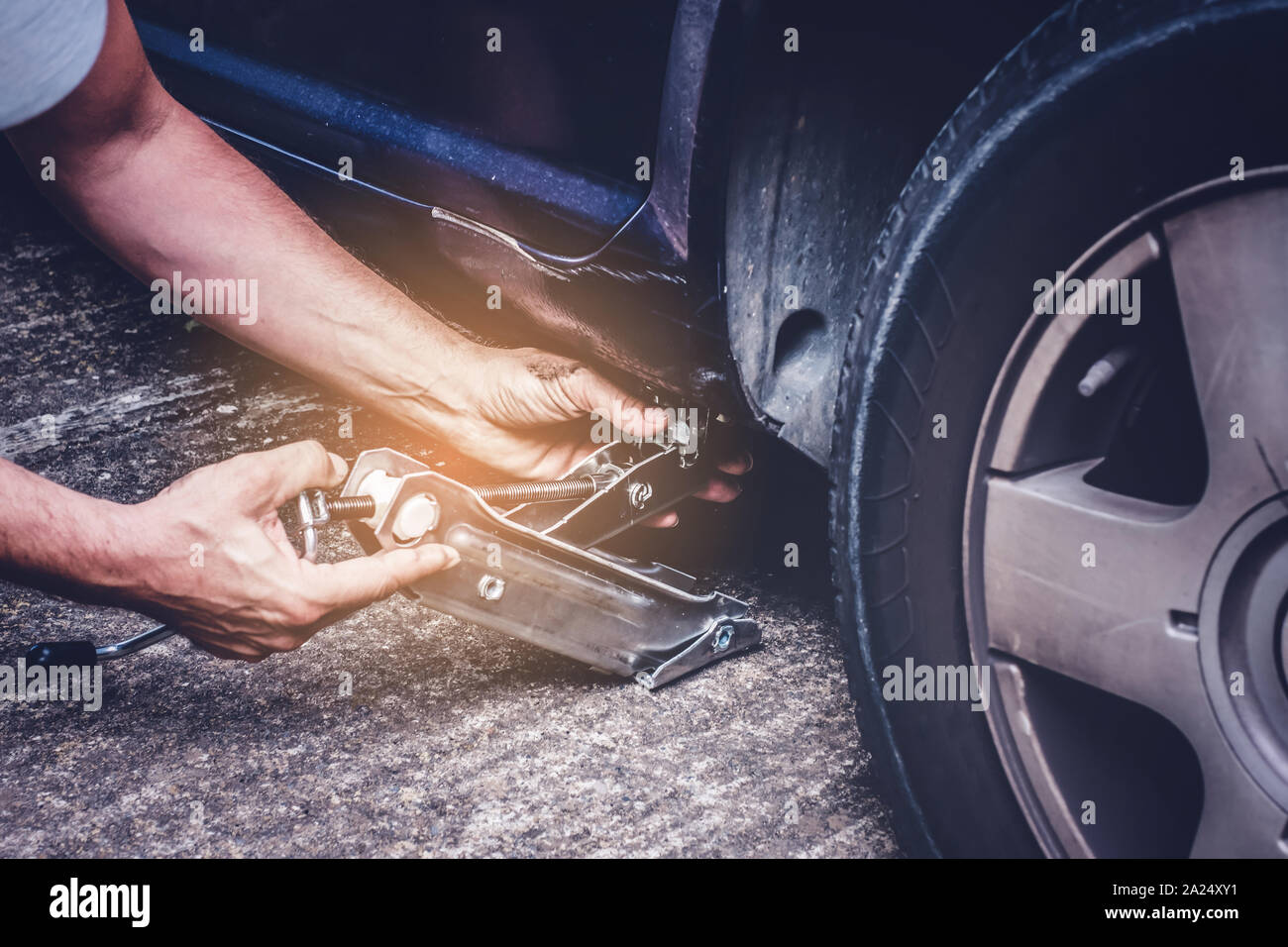 Mann anheben Auto mit Jack Schraube für Reifenwechsel der Reifenpanne Rad - Reifenwechsel oncept Stockfoto