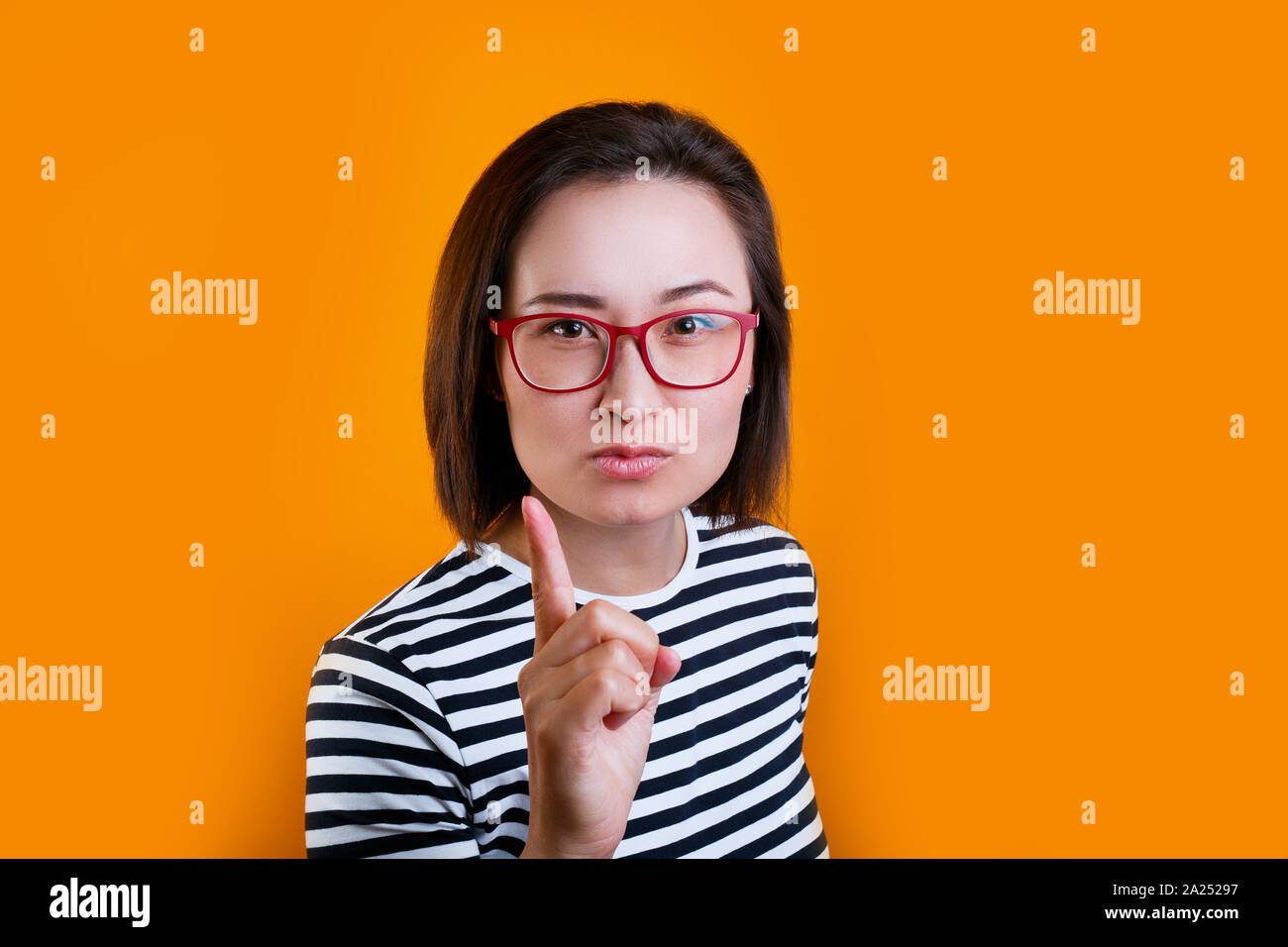 Unzufrieden asiatische Frau in roten Gläsern Warnung über gelben Hintergrund Stockfoto