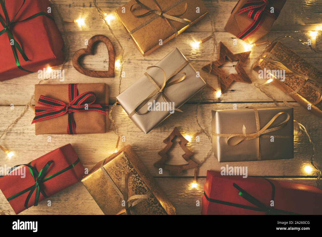 Verpackte Weihnachtsgeschenke mit Lichtern auf weißem Holz- Hintergrund Stockfoto