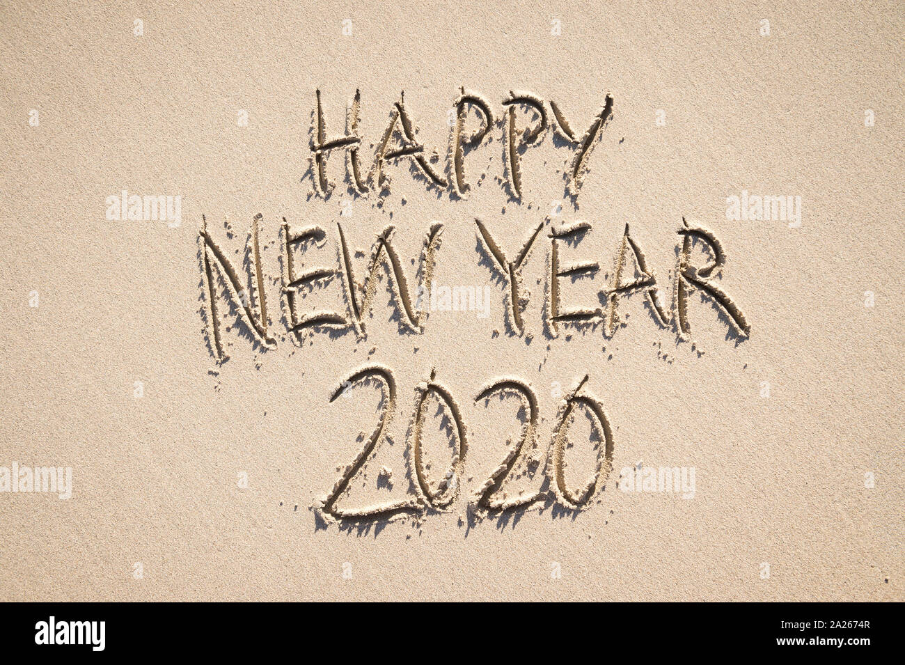 Frohes Neues Jahr 2020 Nachricht handschriftlich in angehobener strukturierte Briefe an einem Sandstrand mit glatten Raum kopieren Stockfoto