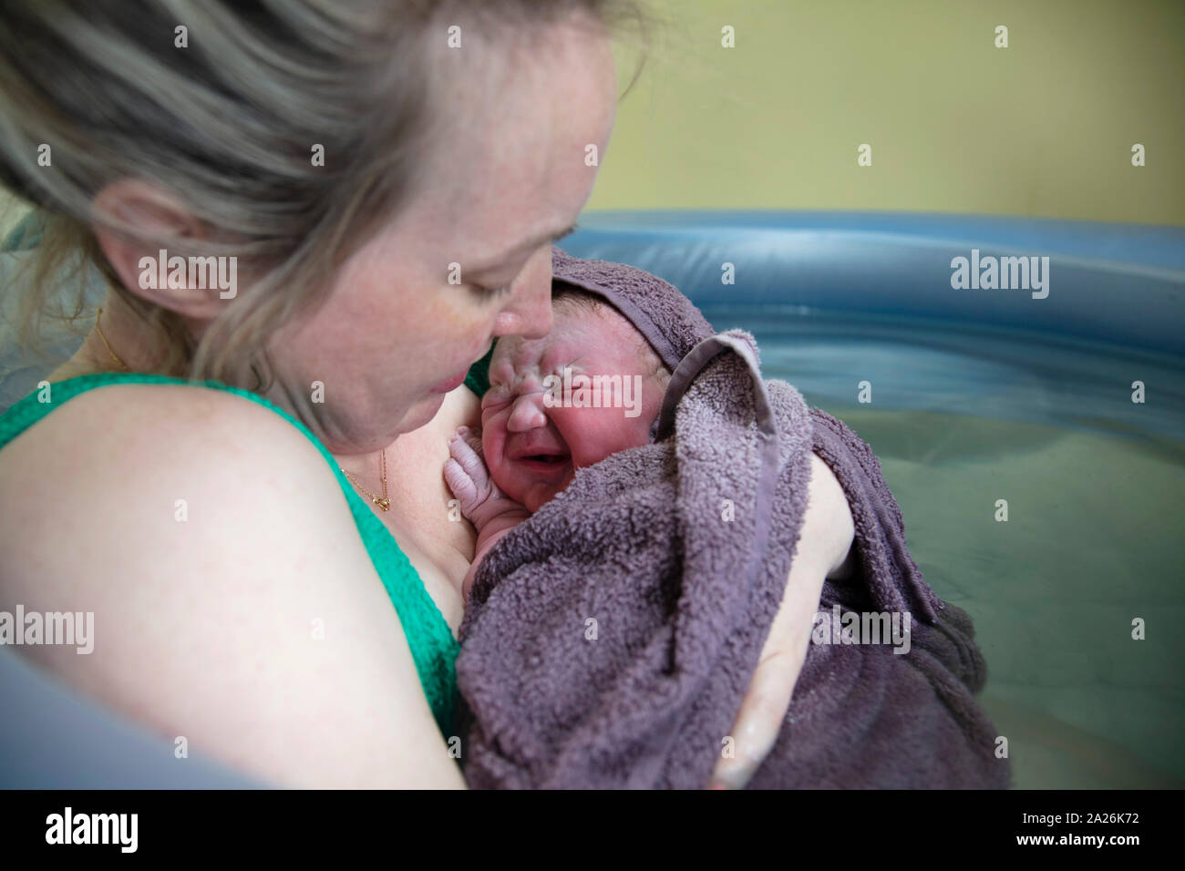 Eine neue Mutter ihr neugeborenes Baby, das nach einem natürlichen Pool home Geburt Stockfoto