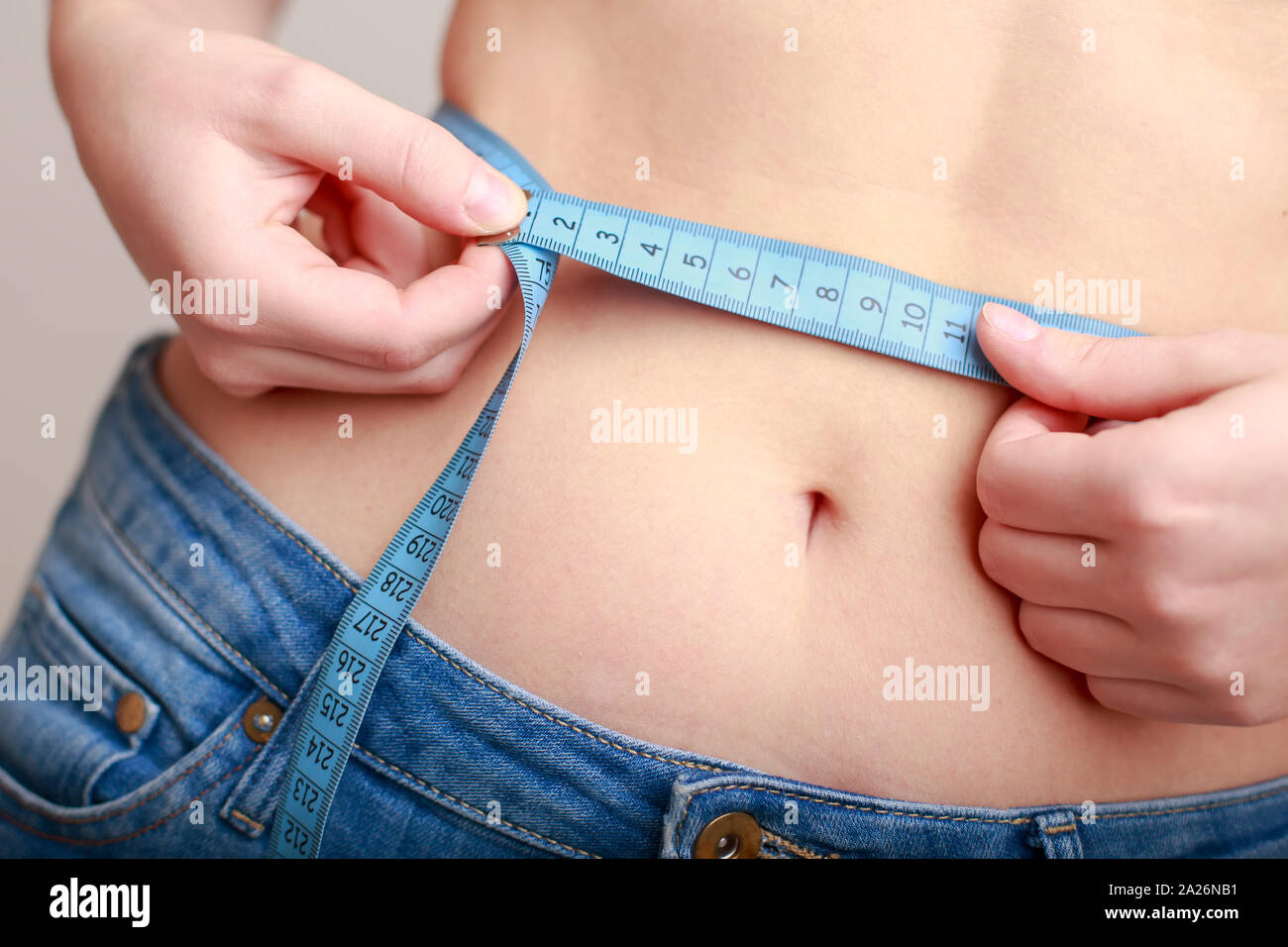 Hellhäutige Frau in Blau Jeans ist mit einer schönen schlanken Taille gemessen Stockfoto