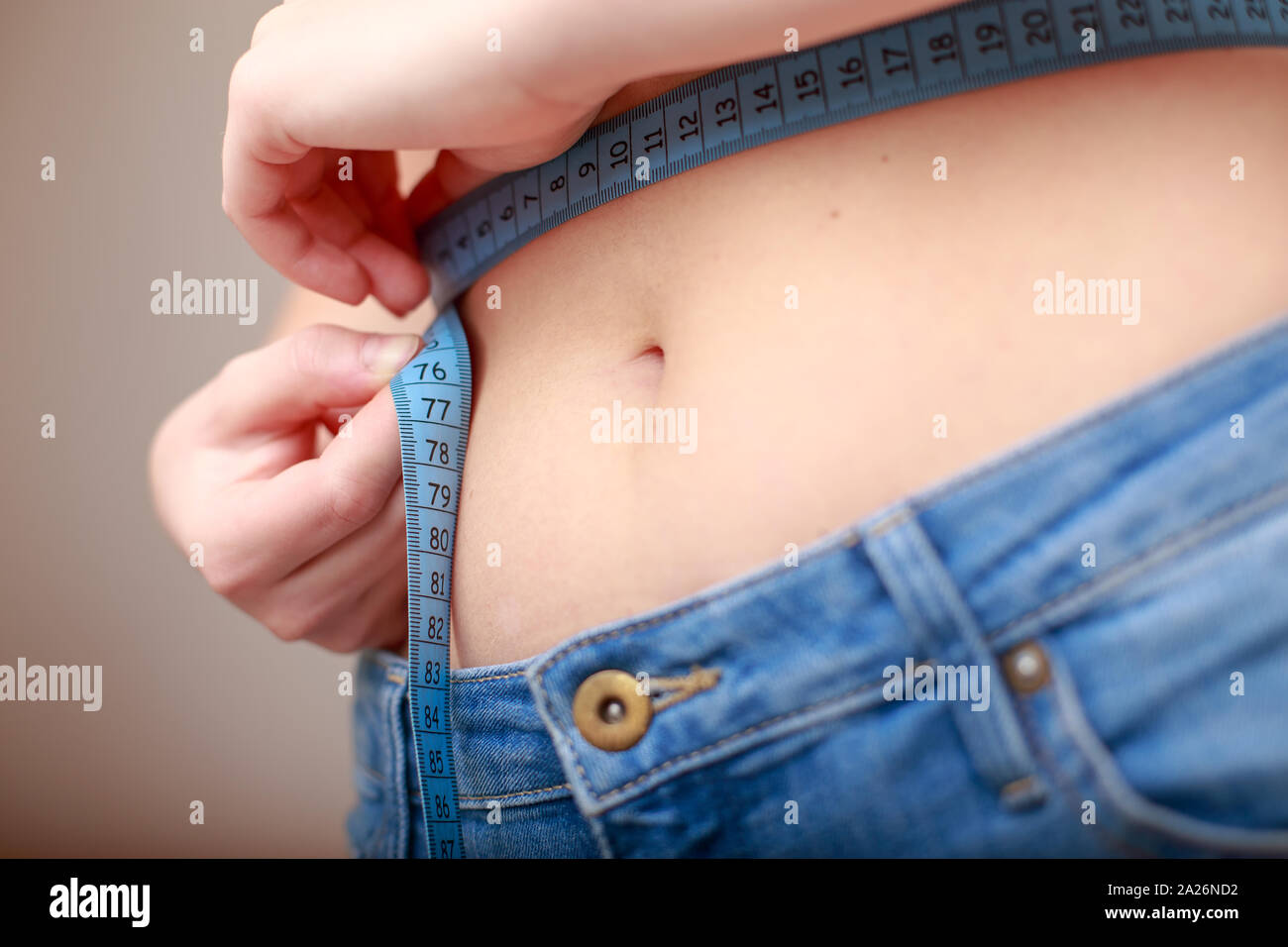 Hellhäutige Frau in Blau Jeans ist mit einer schönen schlanken Taille gemessen Stockfoto