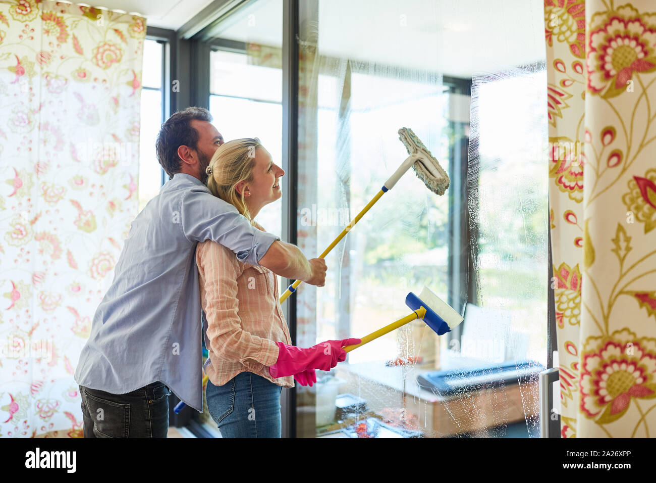 Glückliches Paar mit Scheibenwischer am Fenster reinigen Glas während der Reinigung der Haus Stockfoto