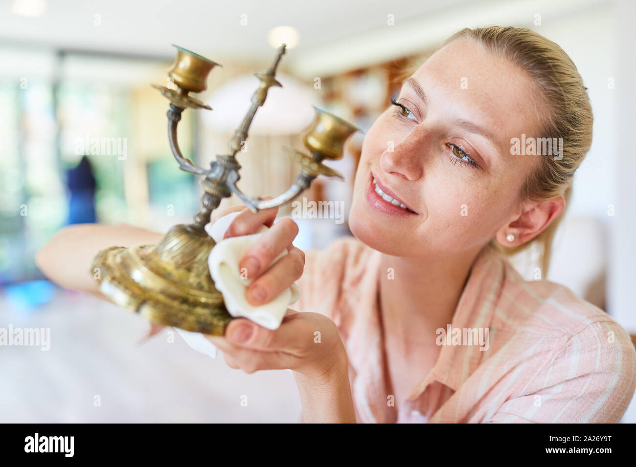Hausfrau als Putzfrau polieren Messing Kerzenhalter im Frühling Reinigung Stockfoto