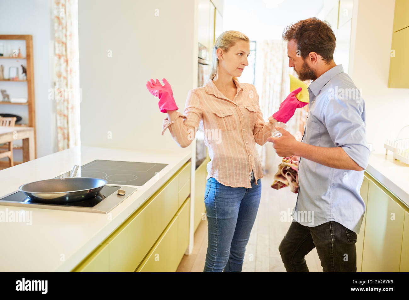 Paar diskutieren in der Küche über die Verteilung der Rollen bei der Reinigung im Haushalt Stockfoto