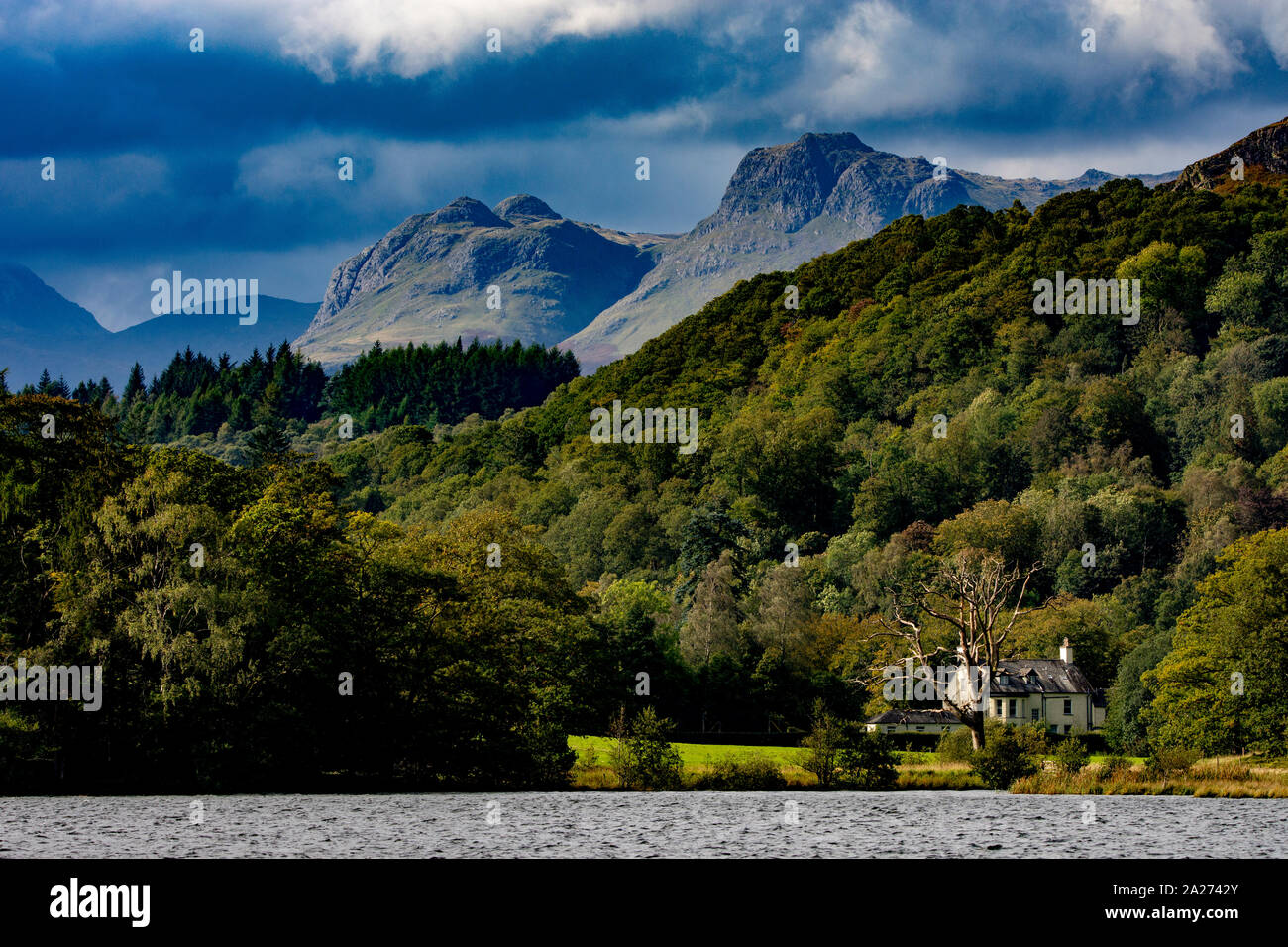 Blick über den See Windermere im Lake District in Großbritannien. Die Berge im Hintergrund perfekt beleuchteten durch die untergehende Sonne Stockfoto