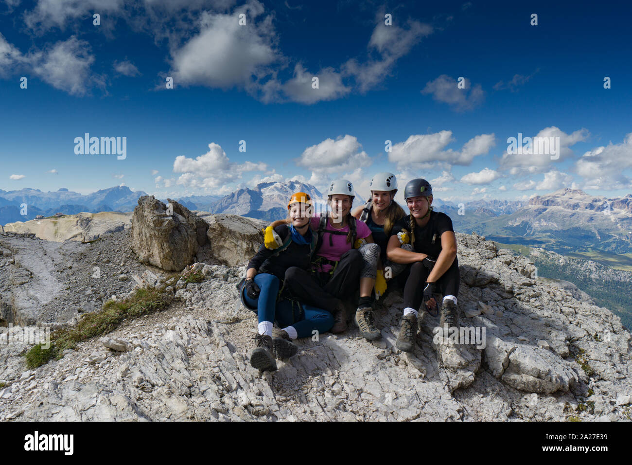 Vier attraktive Frauen Bergsteiger Umarmung und Lächeln auf einem Berg nach einem anstrengenden Aufstieg in die italienischen Dolomiten in der Nähe von Cortina d'Ampezzo Stockfoto