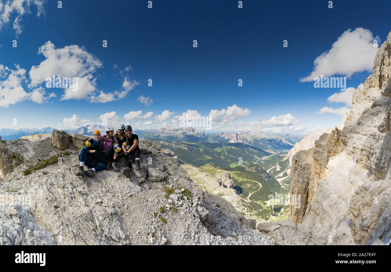 Panorama Ansicht von vier attraktive Frauen Bergsteiger Umarmung und Lächeln auf einem Berg nach einem anstrengenden Aufstieg in die italienischen Dolomiten in der Nähe von Cortina d'A Stockfoto
