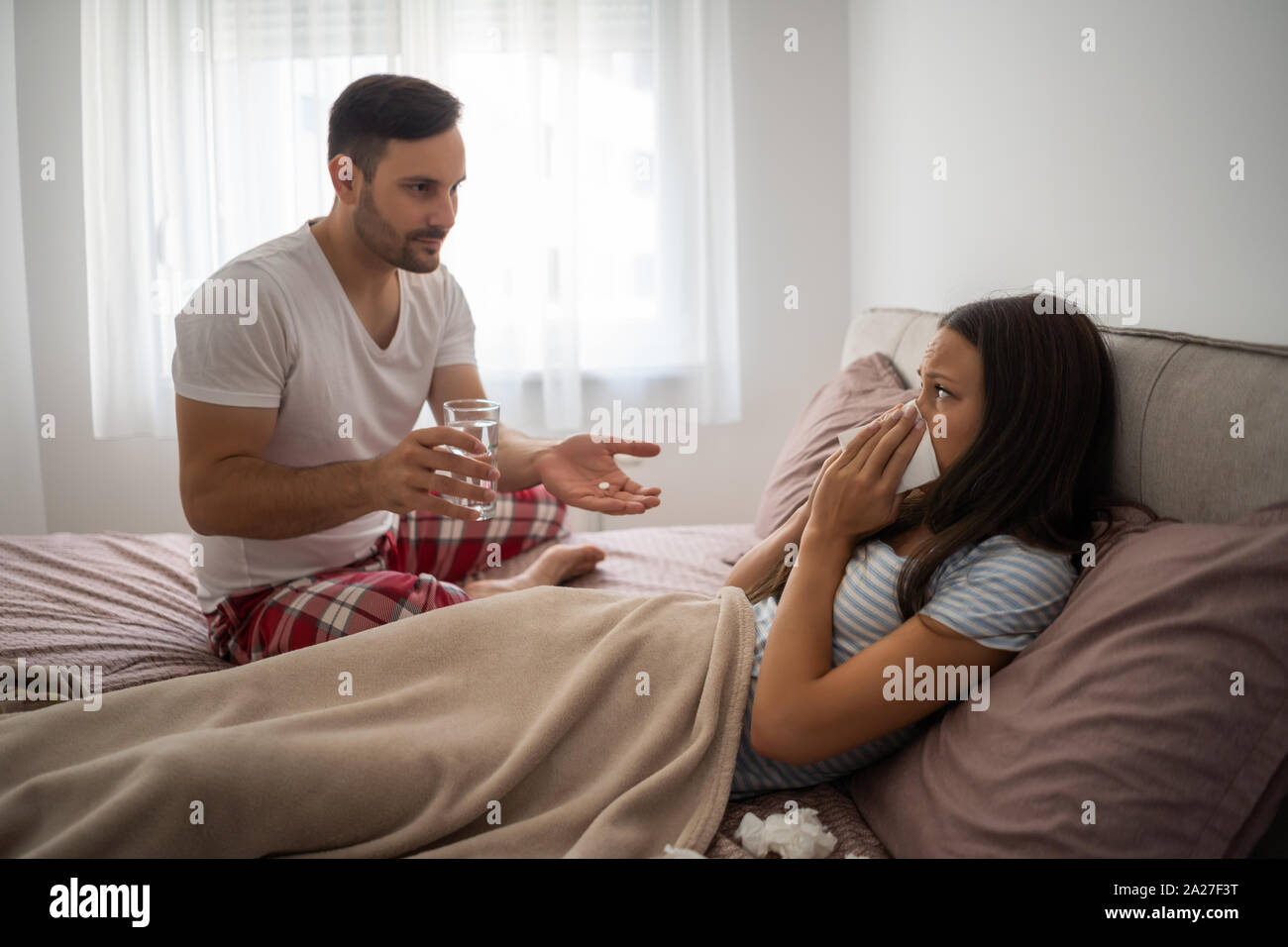 Frau ist krank, Mann ist ihre Pillen gaving. Stockfoto