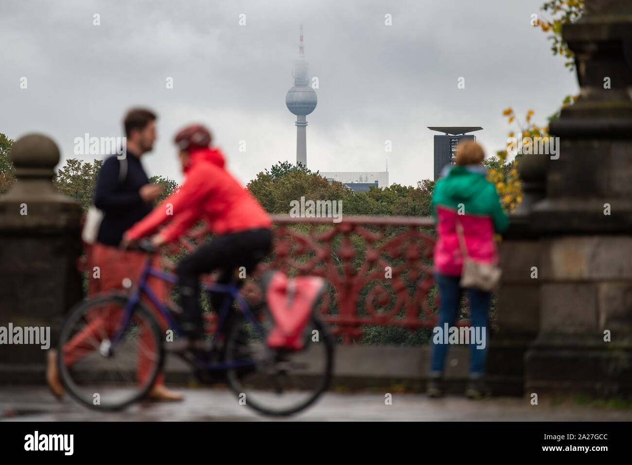 01. Oktober 2019, Berlin: Menschen Überqueren einer Brücke im Nieselregen. Der Berliner Fernsehturm im Hintergrund ist leicht in Wolken gehüllt. Foto: Arne Immanuel Bänsch/dpa Stockfoto