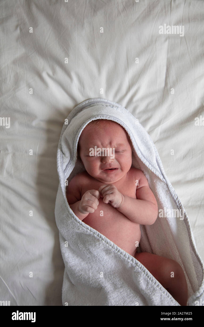 Ein schreiendes Baby in einer weißen Decke gewickelt Stockfoto