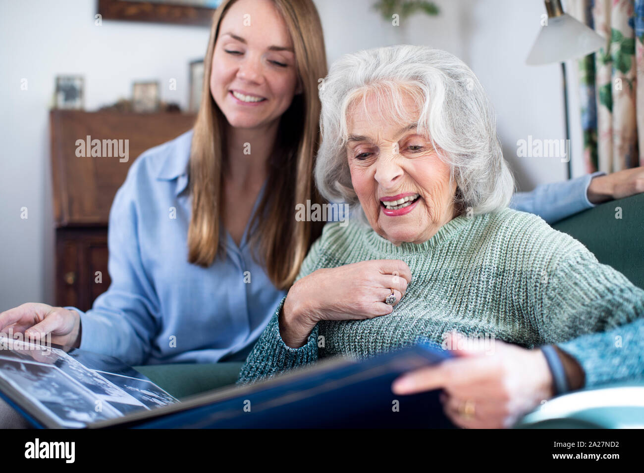 Großmutter an Fotoalbum mit Erwachsenen Enkelin Suchen Stockfoto
