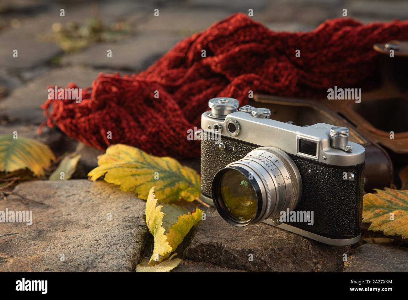 Herbstliche Stimmung noch Leben: vintage Kamera, braunem Leder Holster, roter Schal und Blätter zur Festlegung auf Pflaster Stockfoto