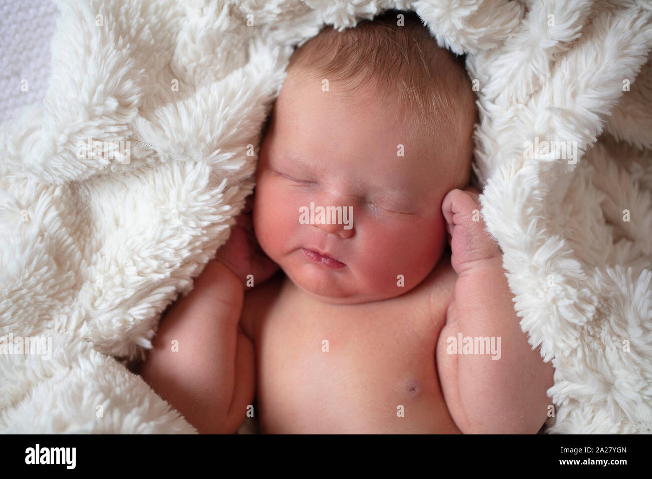 Eine schöne New Born Baby schlafen in einem Fell Decke Stockfoto