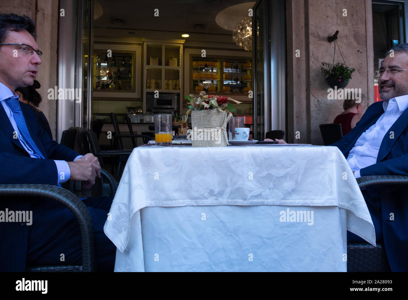 Zwei lokale Römische business Männer, tragen Anzüge und Krawatten, trotz der Hitze, über dem Mittagessen plaudern in einem traditionellen Open air Restaurant auf der Straße. Stockfoto