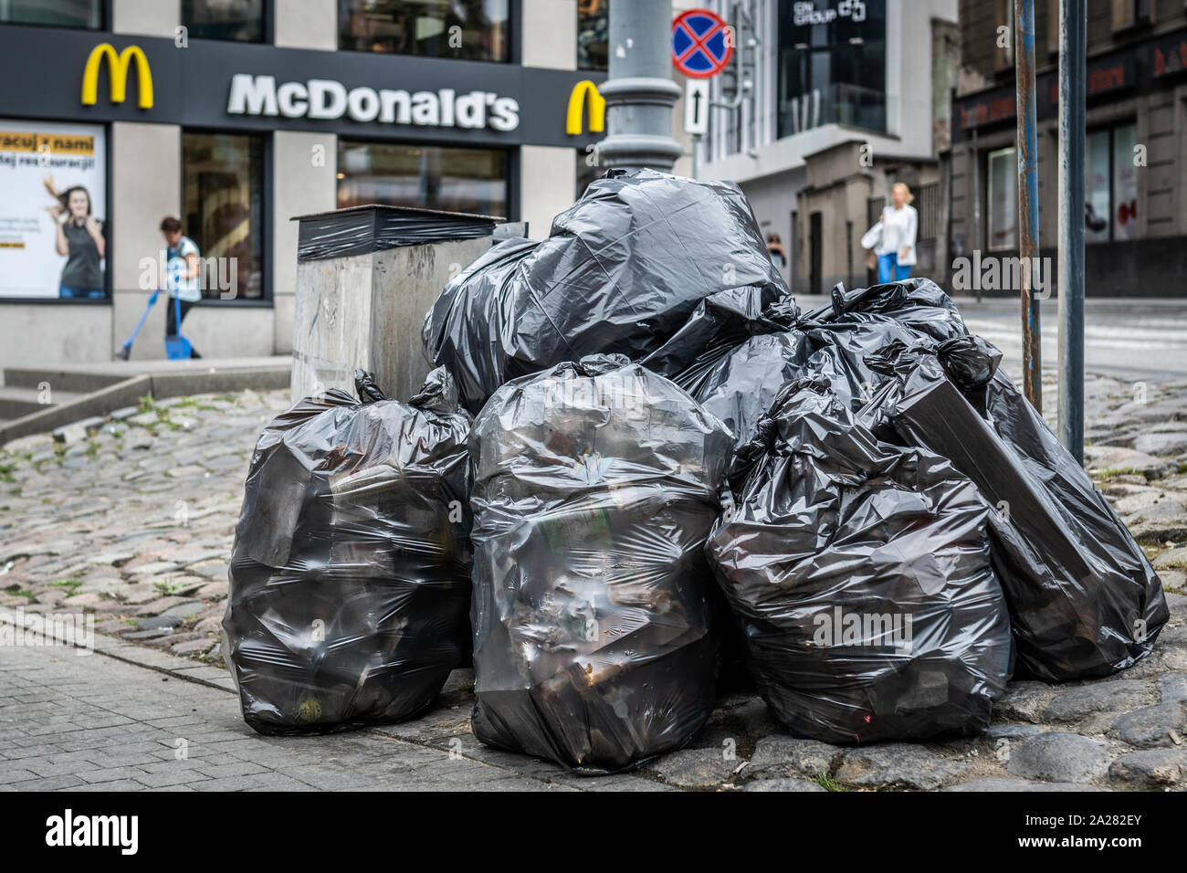 Stapel Plastiktüten voller Müll vor einem Fast Food Restaurant. Stockfoto