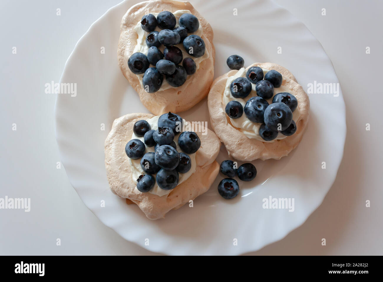 Pavlov Kuchen mit Sahne und frischen Blaubeeren auf einer weißen Platte Stockfoto