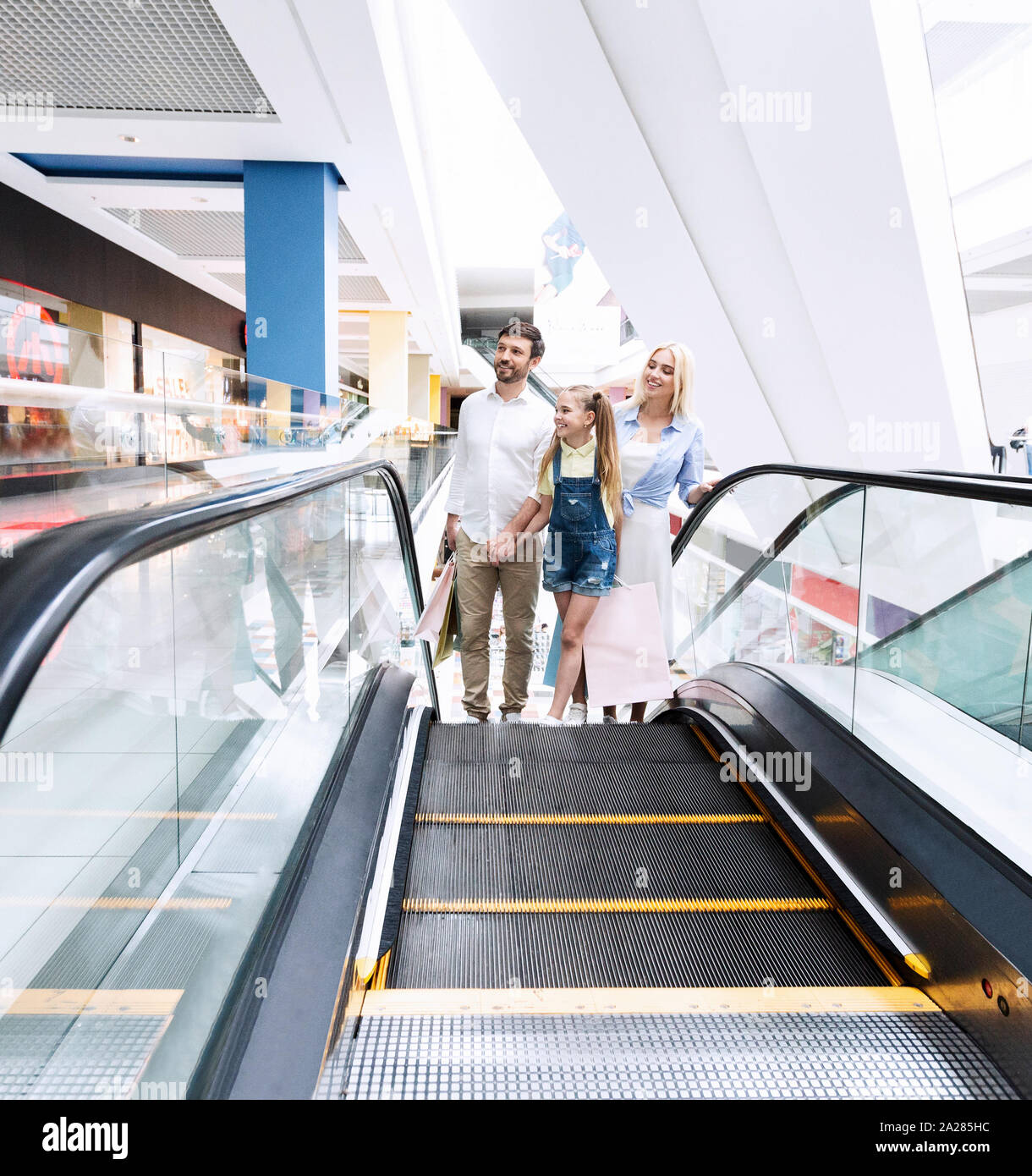 Eltern und Tochter gehen, auf der Rolltreppe im Einkaufszentrum Stockfoto