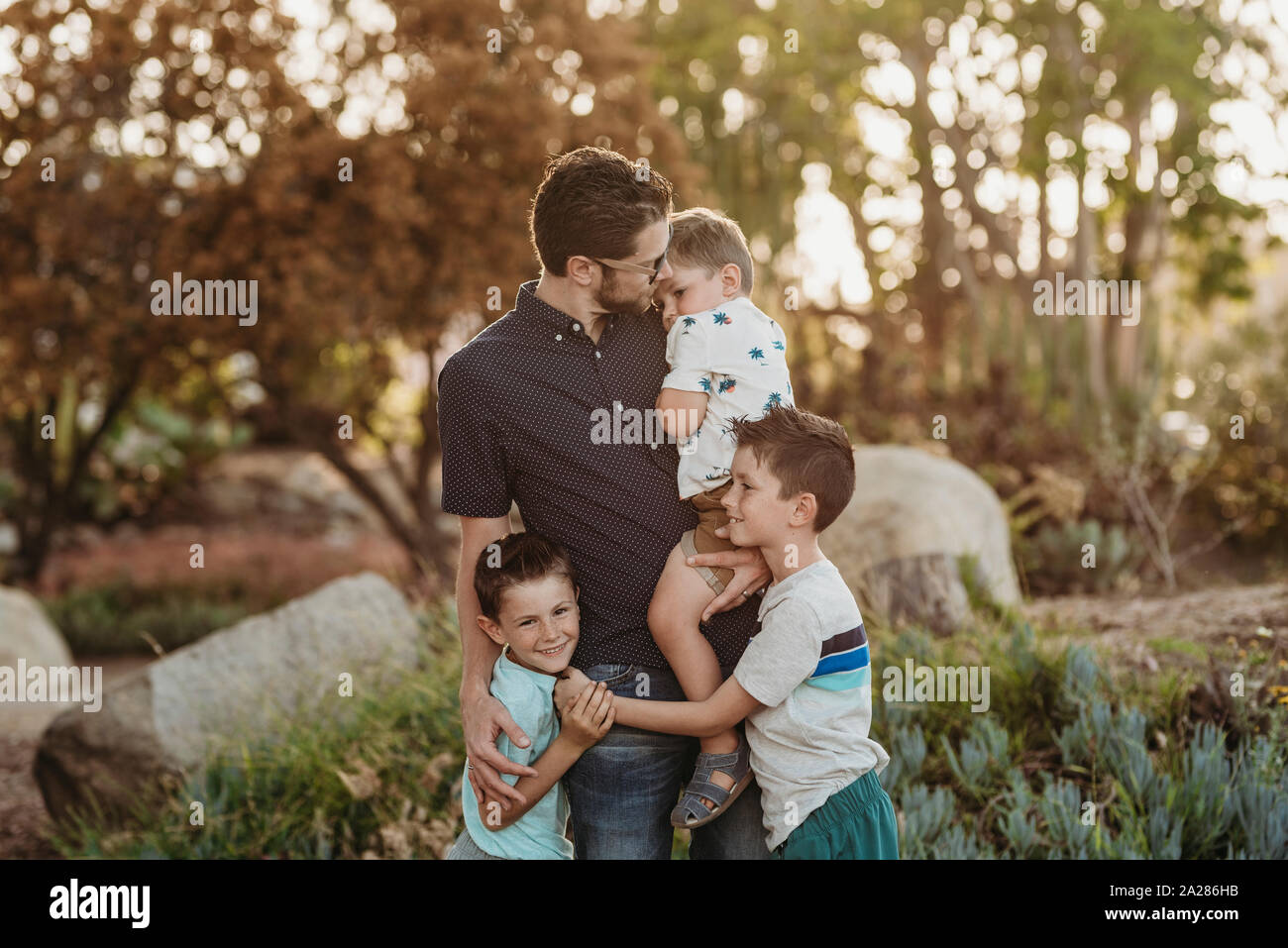 Portrait von Papa Holding toddler Boy und umarmen Söhne im sonnigen Garten Stockfoto