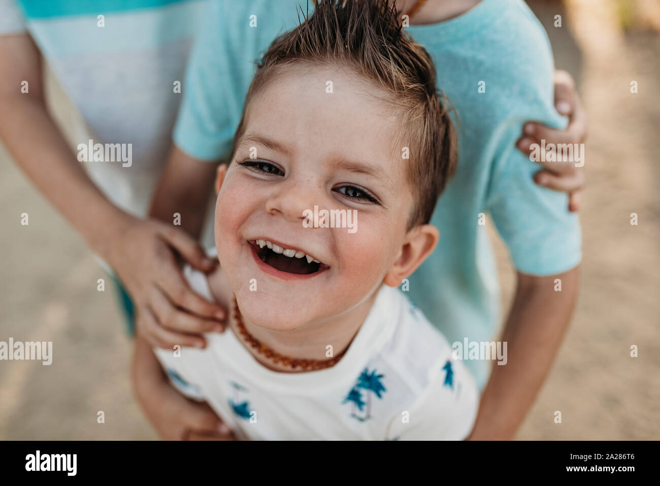 In der Nähe der Jugendlichen 2 Jahre alten Lächeln auf die Kamera während der Brüder umarmte ihn Stockfoto