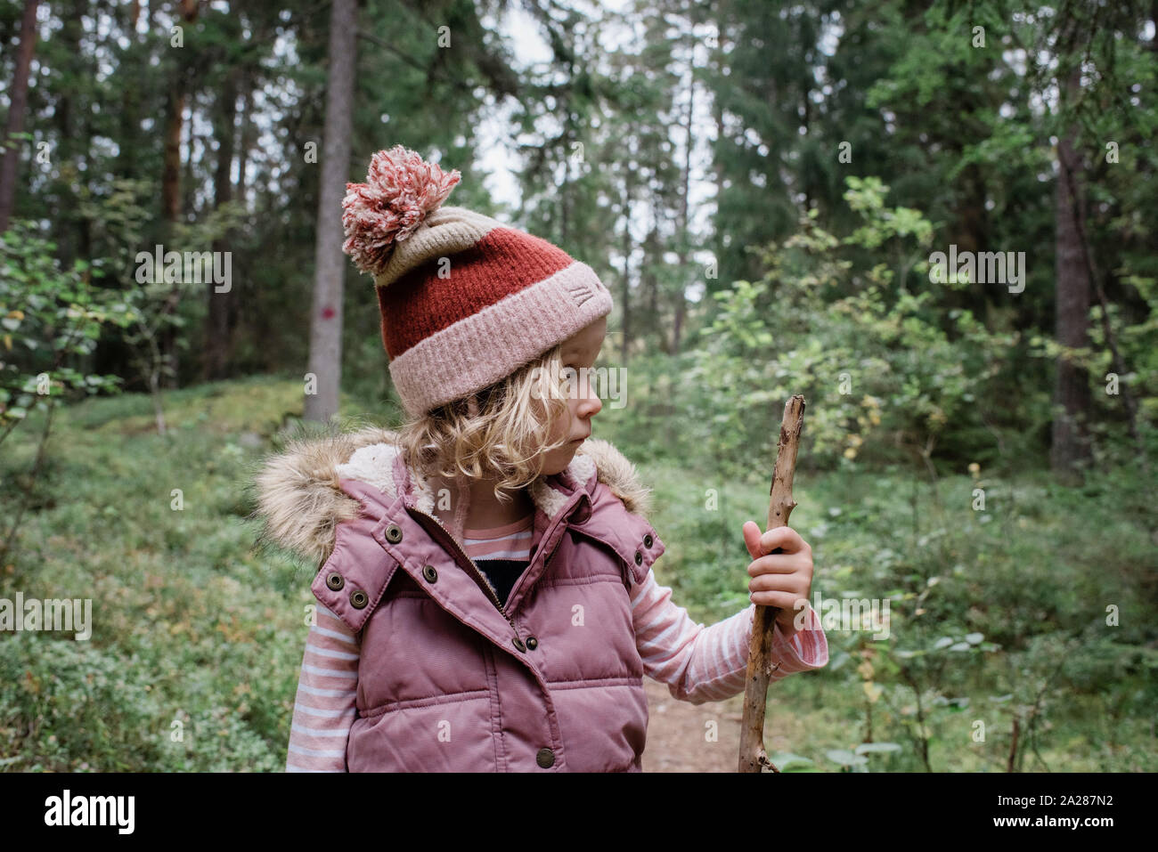 Junge Mädchen stand in einem Wald an ihrem Gehstock suchen Denken Stockfoto