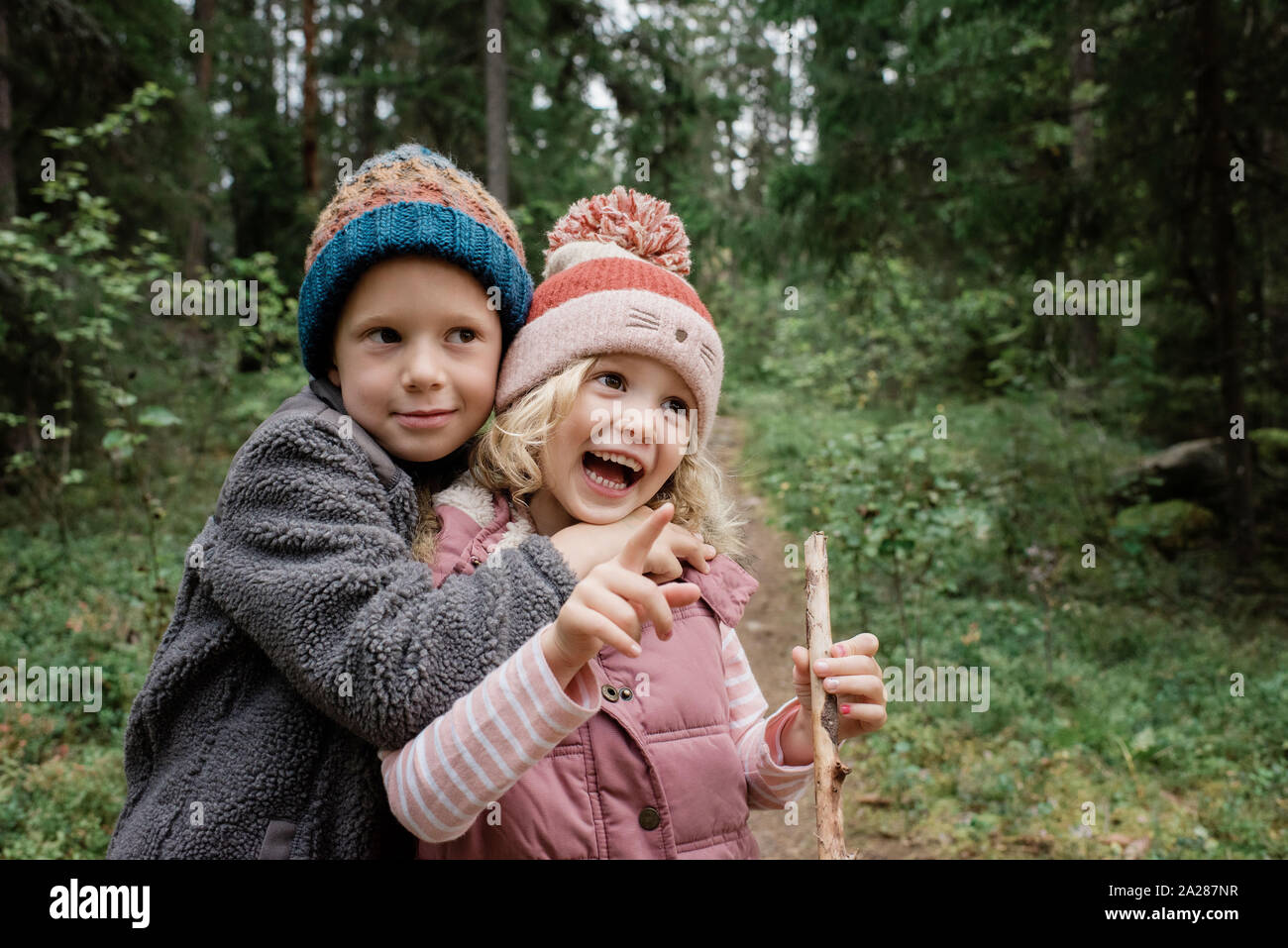 Bruder seine Schwester lachen, während man durch den Wald umarmen Stockfoto