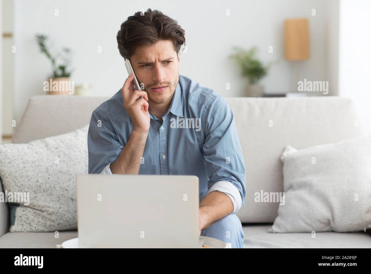 Kerl in unangenehmen Gespräch Arbeiten am Laptop zu Hause Stockfoto