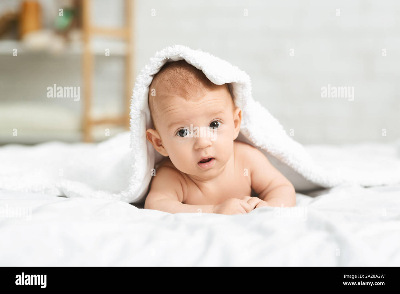 Portrait von niedlichen neugeborenen Jungen heraus spähen unter der Decke Stockfoto